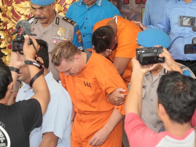 Police officer escorts two William Cabantog and David Van Iersel (behind) during press conference in Bali. Picture: J.P. Christo